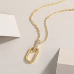 Load image into Gallery viewer, A sleek vertical bar pendant necklace with pavé-set round-cut moissanite stones, featuring a polished golden oval link suspended below, displayed against a neutral background.