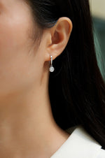 Load image into Gallery viewer, Close-up of a person wearing Éclat Bezel Moissanite Earrings.
