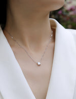 Load image into Gallery viewer, Éclat Cube Moissanite Necklace worn by a person in a white outfit.