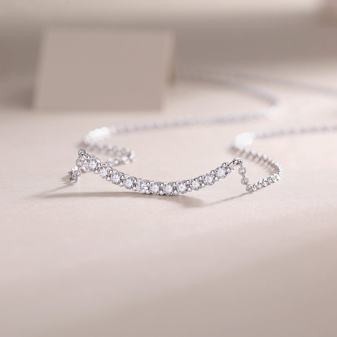 Arc Pavé Moissanite Necklace featuring a graceful curved bar adorned with round-cut moissanite stones, displayed against a light background.