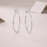 A pair of silver hoop earrings with round-cut moissanite stones set in a three-prong setting.