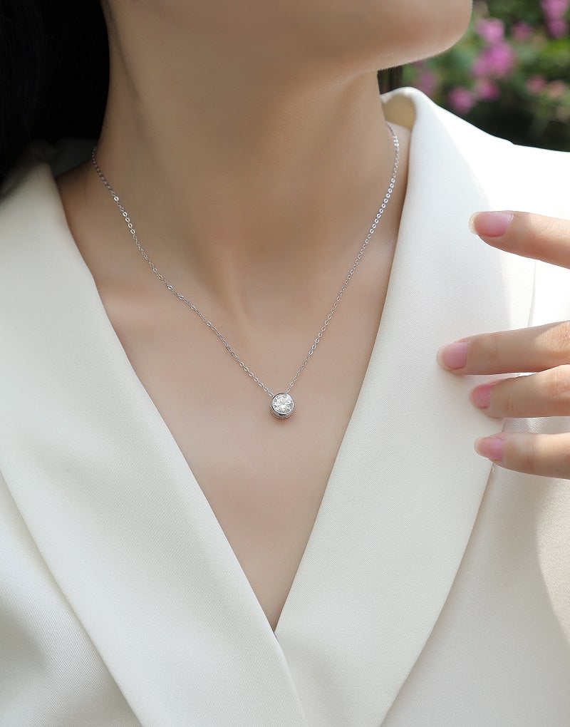 Éclat Bezel Moissanite Necklace worn by a person in a white outfit.