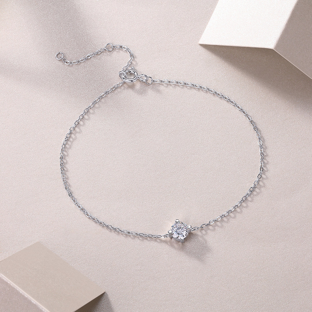 A silver bracelet featuring a single round-cut moissanite stone, displayed on a neutral background.