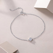 A silver bracelet featuring a single round-cut moissanite stone, displayed on a neutral background.