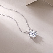 A solitaire moissanite necklace with a round-cut stone in a six-prong setting, displayed on a chain against a neutral background.