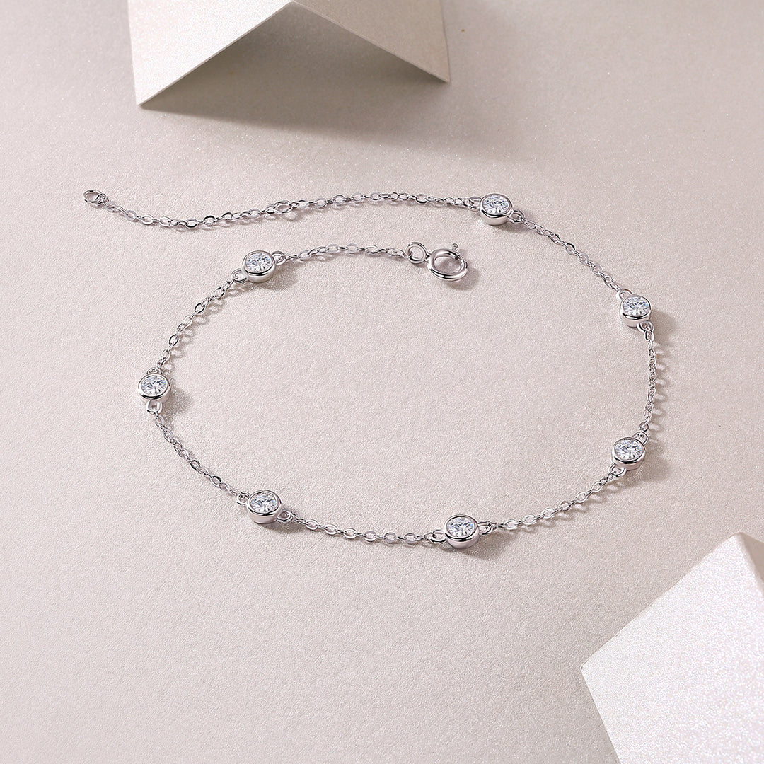 A silver bracelet with round-cut moissanite stones set in bezel settings.