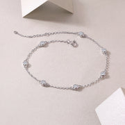 A silver bracelet with round-cut moissanite stones set in bezel settings.