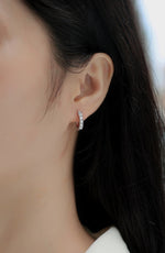 Load image into Gallery viewer, Close-up of an ear wearing Éternelle Brillance Huggie Moissanite Earrings
