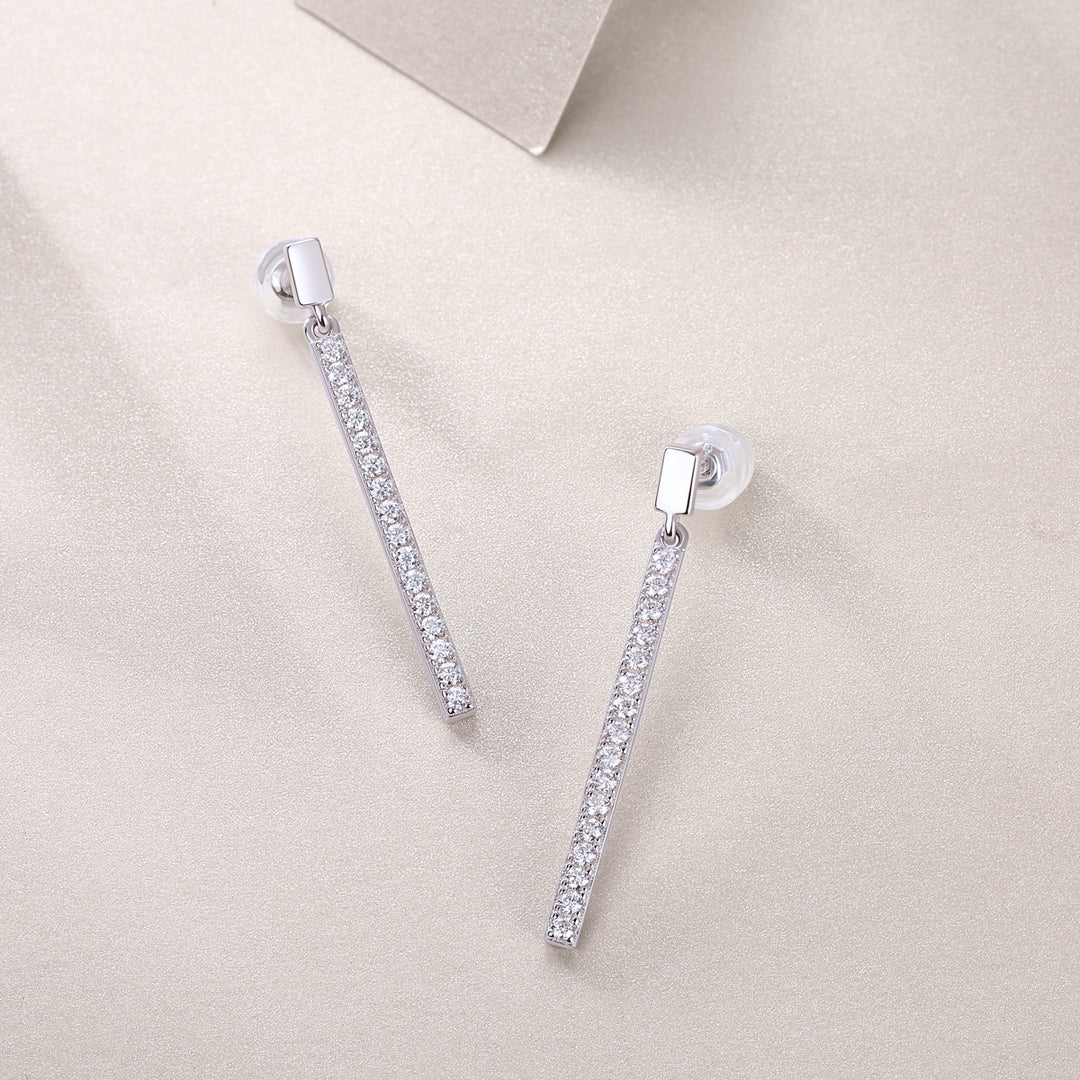 A pair of pave moissanite earrings with a silver bar design and round-cut moissanite stones set in them, displayed on a neutral background.