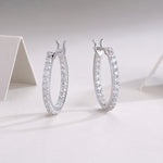 Load image into Gallery viewer, A pair of silver hoop earrings with round-cut moissanite stones set in a double-plated band, displayed on a white surface.
